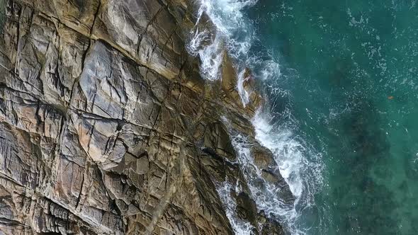 Top aerial view of ocean waves splash against rocks background alt