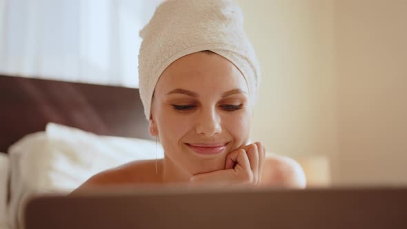 Pleasant Woman in Bath Towel Using Laptop at Hotel Room alt