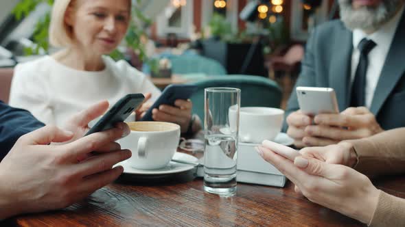 Close-up of Hands Using Smart Phones in Restaurant, Businesspeople Enjoying Social Media During alt