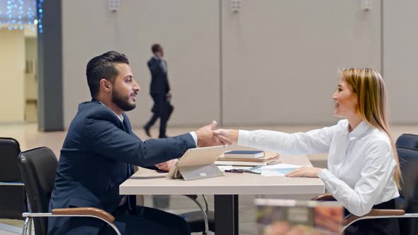 Arabian manager and his Caucasian colleague sitting on the table in cafe