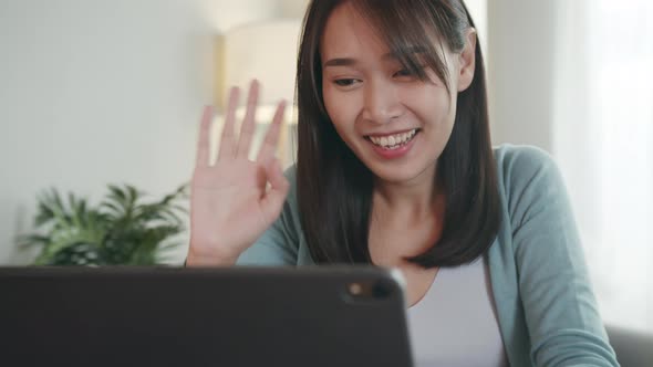 Happy Beautiful Asian Woman waving hand looking at Tablet Screen or webcam having video call