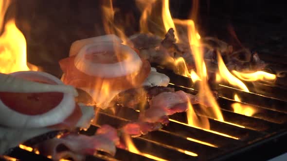 Two juicy delicious-looking burgers roast on the grill. The fire is sizzling