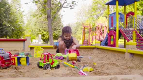 A small girl sitting in a sandbox