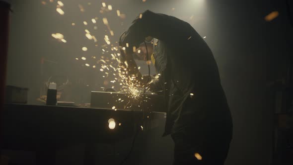 Industrial worker cutting metal with many sharp sparks alt