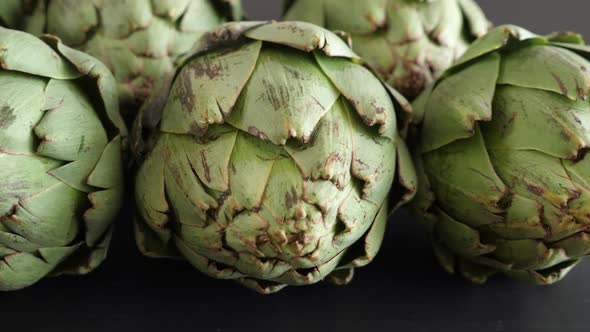 Whole Fresh Artichokes on Black Table alt