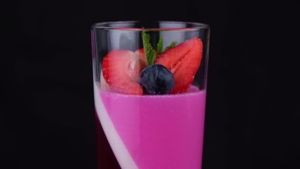 Fruit Jelly with Strawberries and Blueberries in a Rotating Glass on a Black Background a Beautiful