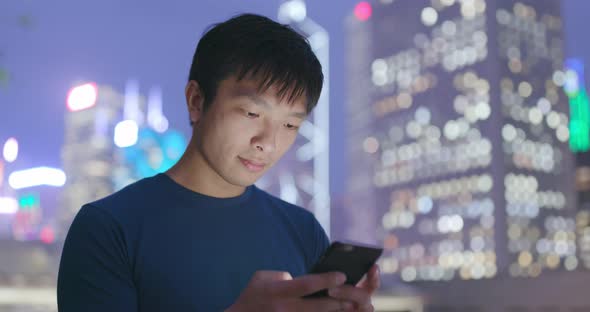 Man use of mobile phone in Hong Kong city at night alt