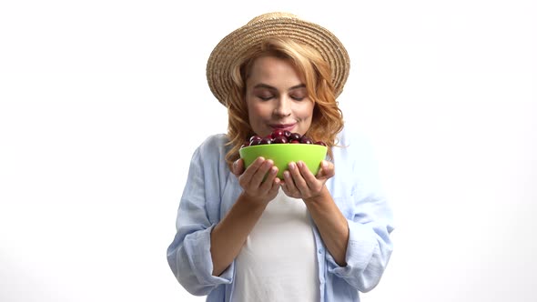Positive Woman in Straw Hat Smelling Fresh Ripe Sweet Cherry Berry Selective Focus Seasonal Fruit alt