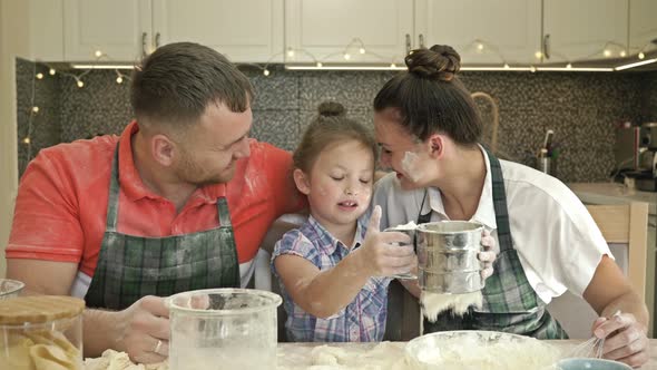 Cheerful Married Couple with a Little Daughter, Cook Some Dough Together, Enjoy Family Activities.