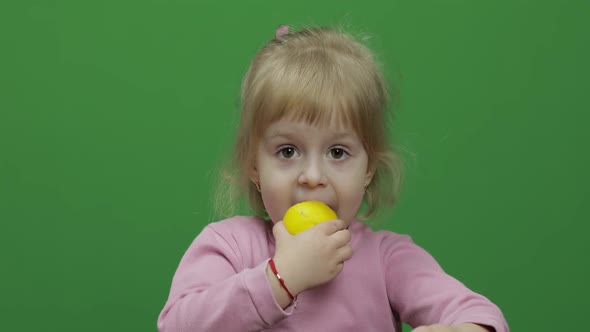 Beautiful Young Girl Eats a Lemon with a Grimace on Her Face, Chroma Key alt