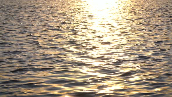 Background of Lake Water Surface with Ripples and Sunlight at Sunset