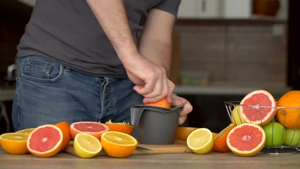 A Man is Squeezes Orange Juice with Citrus Juicer alt