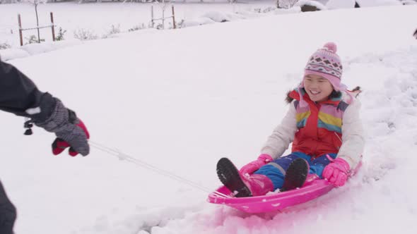 Kids playing and pushing sled in winter snow