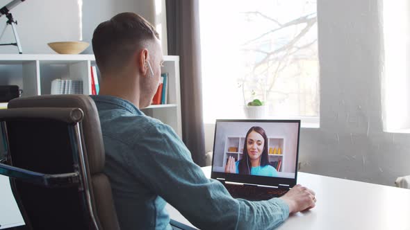 Young male entrepreneur works at home office at the computer. alt