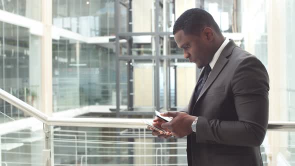 A Black Man Uses His Phone for Business. An African American Business Professional Works on His
