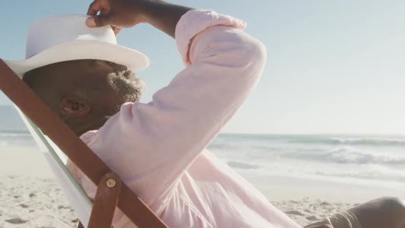 Senior african american man lying on sunbed on sunny beach alt