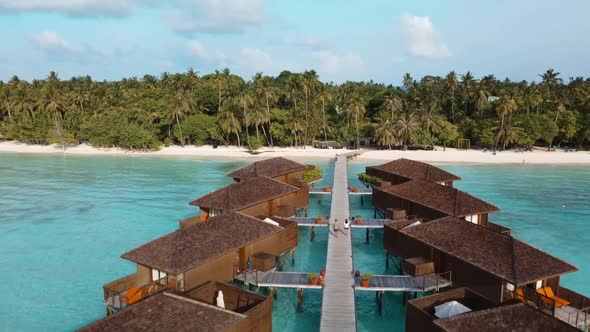 Tourists Walking On Boardwalk Along Water Bungalow By The Sea At An Exotic Resort In Meeru Island, M alt