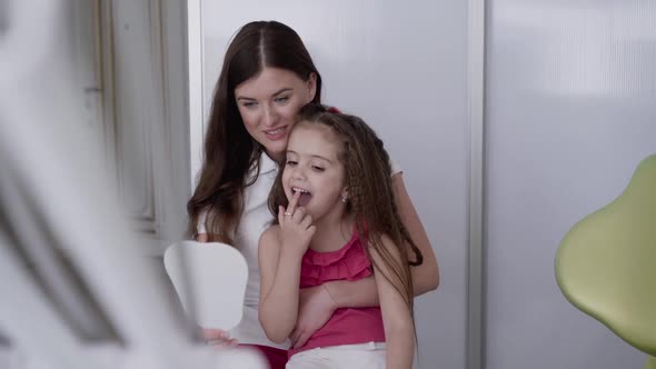 Dentist and Little Client Examining Teeth at Dental Mirror with Smile in Clinic alt