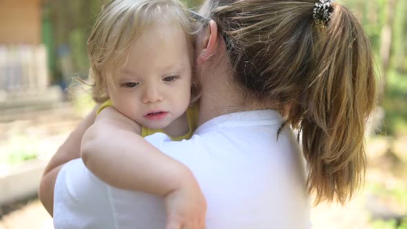 Little Cute Baby Toddler Girl Blonde with Curls on Mother's Arms alt