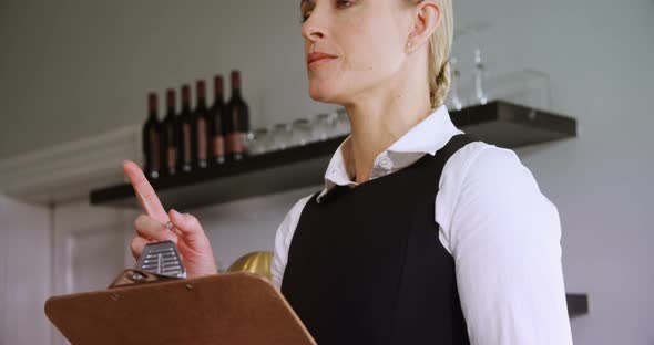 Waitress maintaining record on clipboard alt