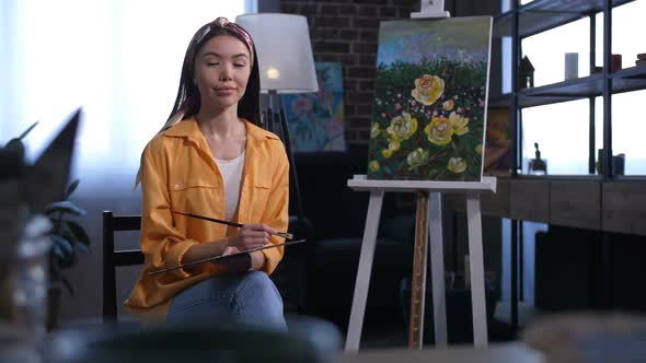 Attractive Asian Female Artist Sitting Near Canvas alt