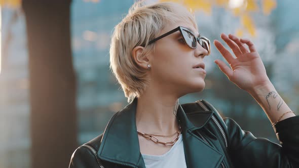 Young Woman with Bright Hair and Sunglasses Posing in Park with Hands Over the Head. Close Up alt
