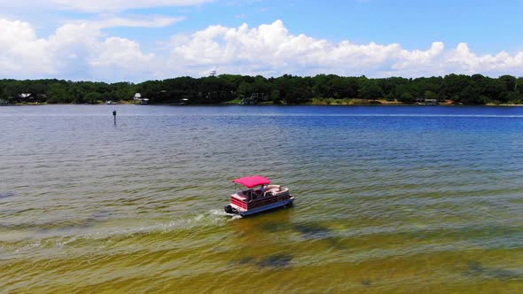 Aerial view panning right of a pontoon boat leaving some small islands near Destin Florida. alt