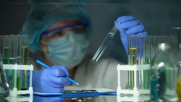 Researcher Analyzing Transparent Blue Liquid, Water Contamination Prevention alt