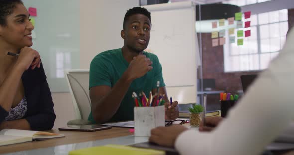 Mixed race business colleagues sitting having a discussion in meeting room alt