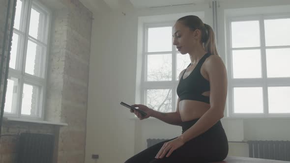 Sportive Girl Using Smartphone After Training At Gym alt