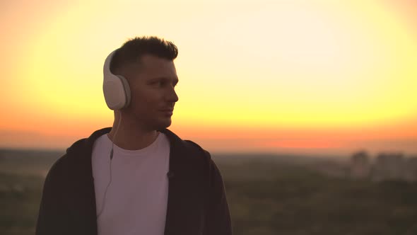 Smiling and Laughing Handsome Young Man Listening Music From His Smartphone in Wireless Headphones alt
