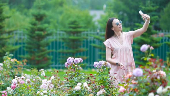 Young Girl in a Flower Garden Among Beautiful Roses. Smell of Roses
