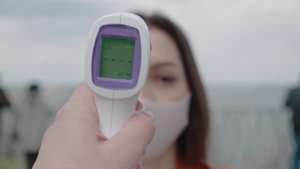 Medical Worker Hand Remote Checks Temperature Woman Checking Health of Woman Walking on the Street alt