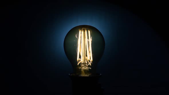 Electric Vintage Edison Light Bulb with a Spiral Flashing on a Blue Background alt