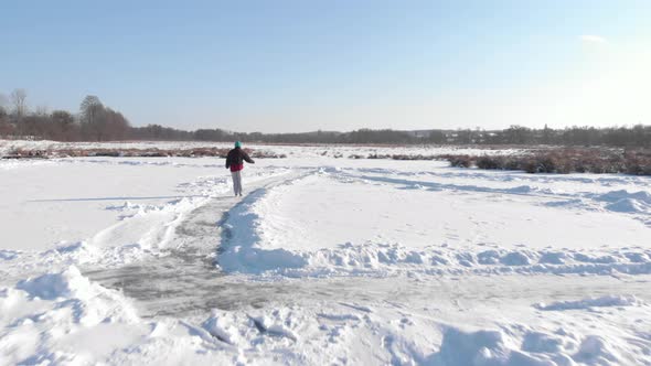 Person rides in white figure skates on frozen lake in winter alt