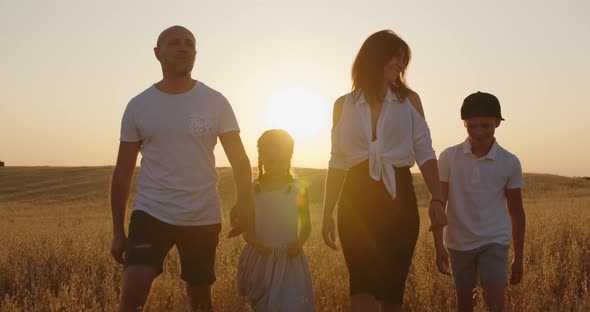 A Family With Children Having Fun And Walking In A Field At Sunset