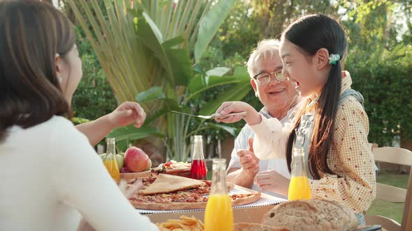 Asian retirement grandfather and pretty granddaughter enjoying to eating pizza together alt