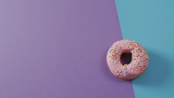 Video of donut with icing on purple and blue background alt