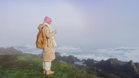 Slow Motion Shot on RED Camera Traveler Woman at Ocean Cliffs on Foggy Morning alt