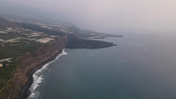 Aerial forward along coast and solidified lava flowed in sea after eruption. La Palma island alt