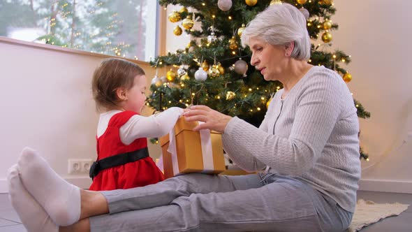 Grandmother and Baby Girl Opening Christmas Gift alt