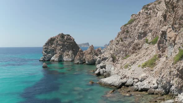 Slow Aerial Flight Over Turquoise Blue Ocean with Rocky Cliff Coast alt