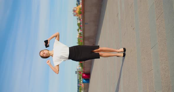 A Young Businesswoman Walks Along the Embankment and Receives a Message  Great News