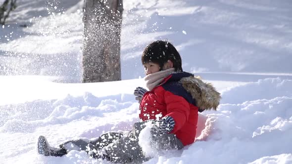 Cute Asian Child Wearing Winter Clothes Playing On Snow In The Park alt