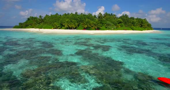 Aerial drone view of a man and woman couple kayaking around a tropical island alt