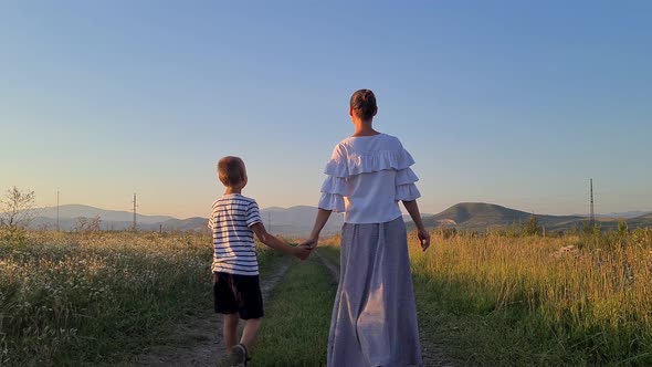 mom and son walk hand in hand across the field