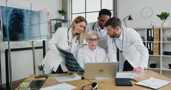 Doctors Working Together During Meeting in Medical Office and Reading Results alt