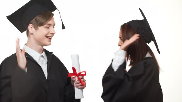 African American Graduate Female Rejoicing with Caucasian Young Male in Black Robe Who Throwing in alt