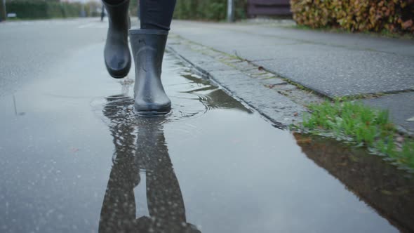 Woman In Boots Walking Through Rain Puddle