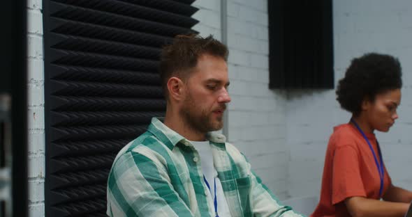 A Man and Woman Work at Laptops Sitting at One Work Desk in a Office alt